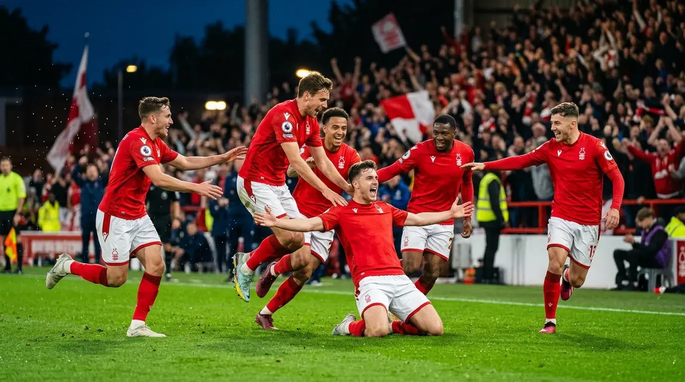 Fussballspieler in roten Trikots jubeln gemeinsam auf dem Spielfeld nach einem Tor bei einem Abendspiel unter Flutlicht
